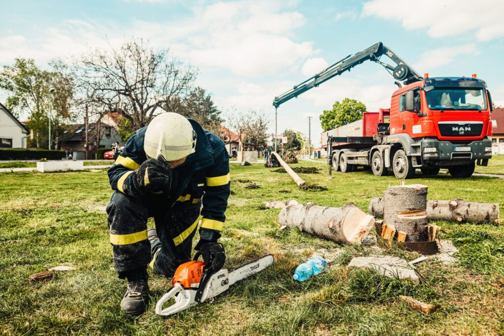 A Uniformed Man Putting the Chainsaw on the Grassy Ground for inspection